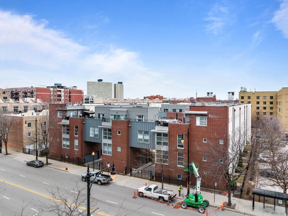Front view of a modern multi-story residential building with brick and panel facade.