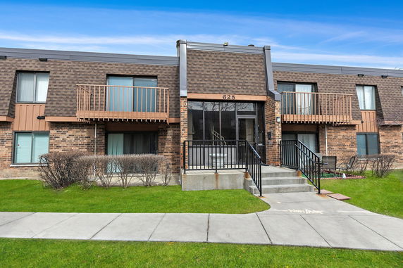 Front view of a two-story building with decorative brown siding and balconies.