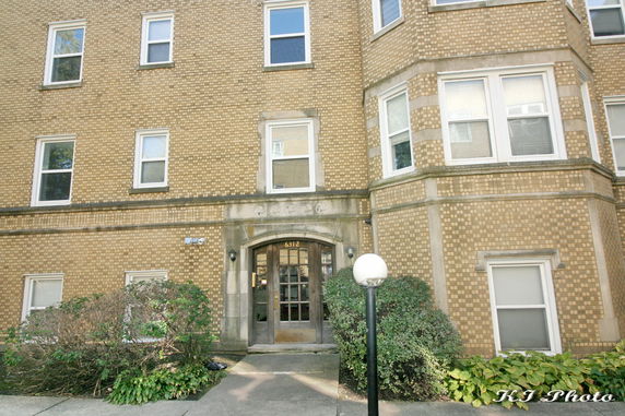 Front view of a multi-story brick building with several windows and an entrance door.