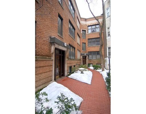 Front view of a multi-story brick apartment building with a red brick walkway.