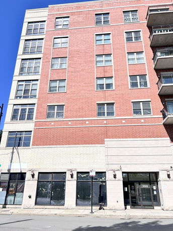Front view of a multi-story brick building with large windows and balconies.