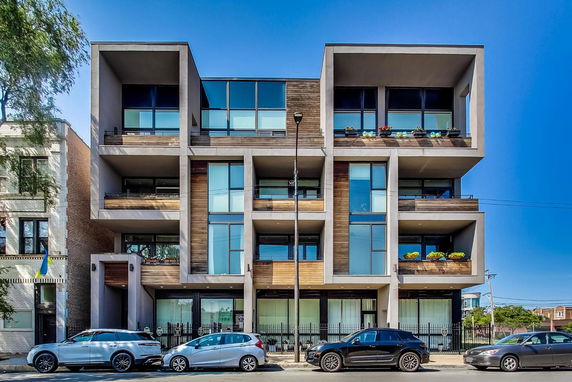 Front view of a modern multi-story building with large windows and balconies.