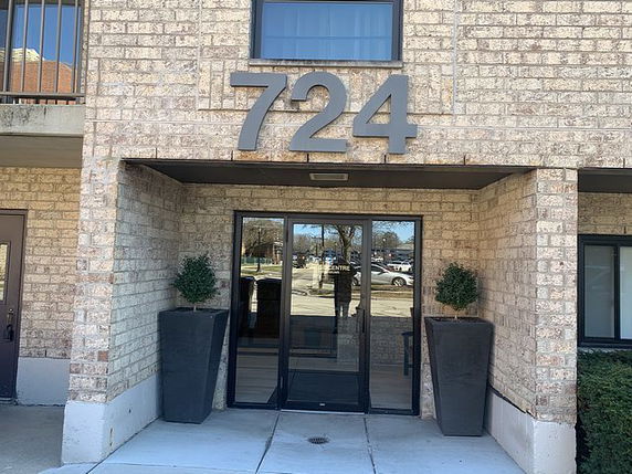 Front view of a building entrance with glass doors and large 724 number sign.
