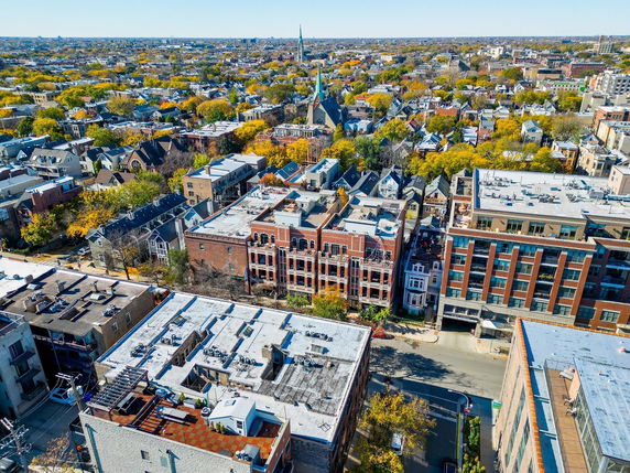 Aerial panoramic view of an urban area with residential buildings and tree-lined streets.