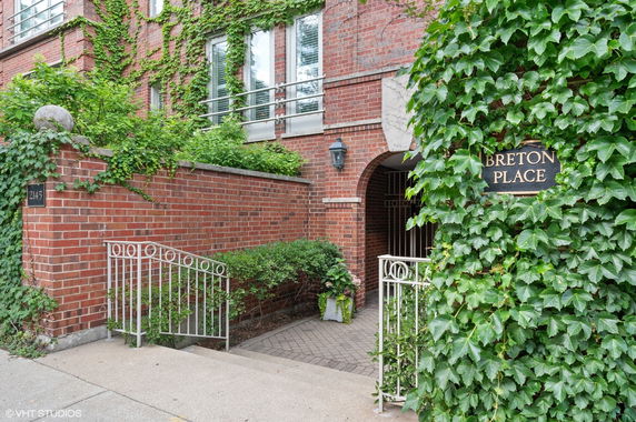 Front view of a brick building with ivy-covered walls and a gated entrance.