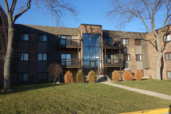 Front view of a multi-story brick apartment building with balconies.