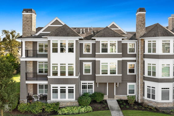 Front view of a multi-story residential building with a stone facade and multiple chimneys.