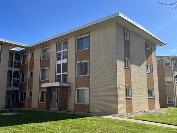Front view of a three-story apartment building with a flat roof and mixed brick facade.