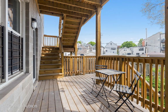 View from an outdoor wooden deck with a staircase and seating area.