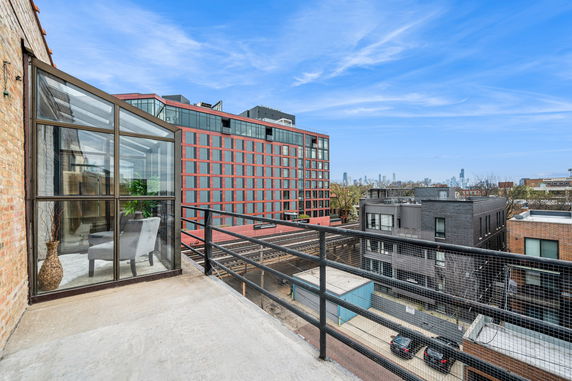 Rooftop balcony with a view of surrounding buildings in an urban area.