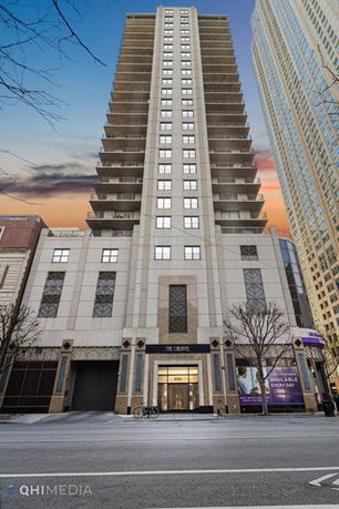 Front view of a tall residential building with multiple balconies.
