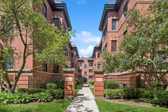 Front view of a red brick building complex with walkways and greenery.