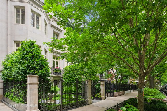 Front view of a multi-story house with decorative windows and a wrought-iron fence.