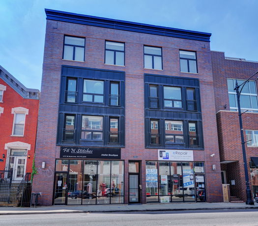 Front view of a four-story brick commercial building with large windows.