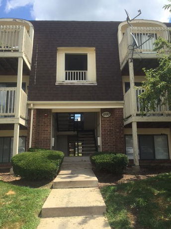 Front view of a multi-story building with balconies and a central staircase.