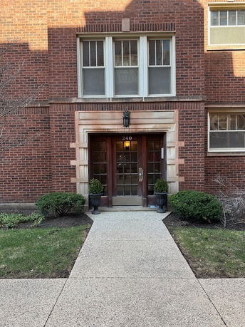 Front view of a brick apartment building entrance with a path leading to the door.