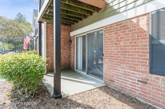 Front view of a brick house with a sliding glass door and American flag.