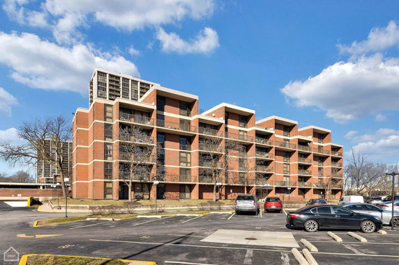 Front view of a multi-story brick apartment building with balconies.