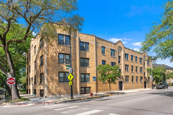 Front view of a multi-story brick apartment building on a street corner.
