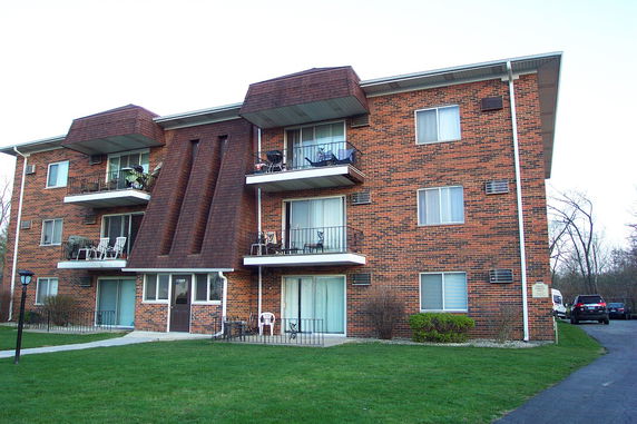 Front view of a three-story brick apartment building with balconies.