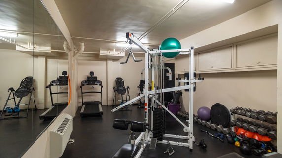 Indoor gym with exercise equipment including treadmills, weights, and a multi-function machine.