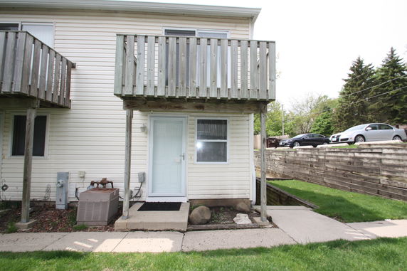 Front view of a two-story house with a wooden balcony and a light-colored exterior.