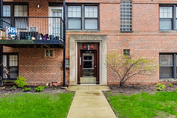 Front view of a brick building with a main entrance door and a small balcony.
