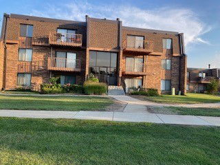 Front view of a multi-story brick apartment building with balconies.