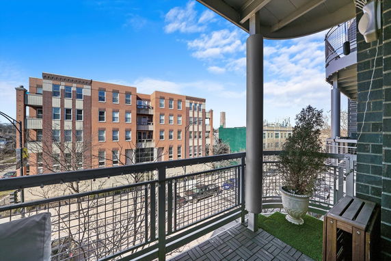 Balcony view overlooking a street with brick apartment buildings.