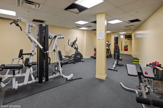 Interior view of a gym with exercise equipment including weights and cardio machines.