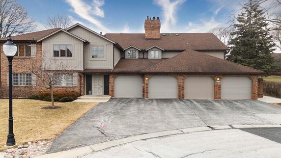 Front view of a two-story house with multiple garages and brick exterior.