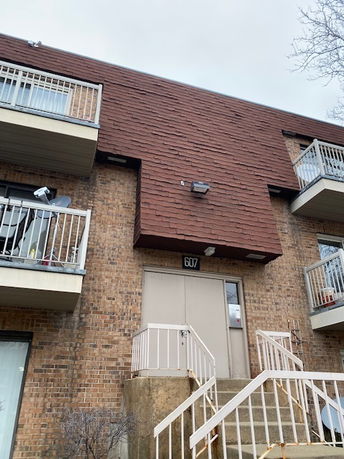Front view of a multi-story building with brick exterior and balconies.