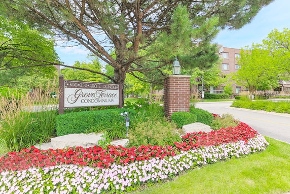 Front view of a condominium complex with signage and landscaped entrance.