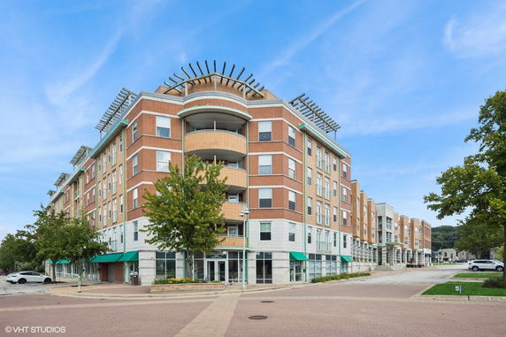 Front view of a multi-story apartment building with balconies and green awnings.