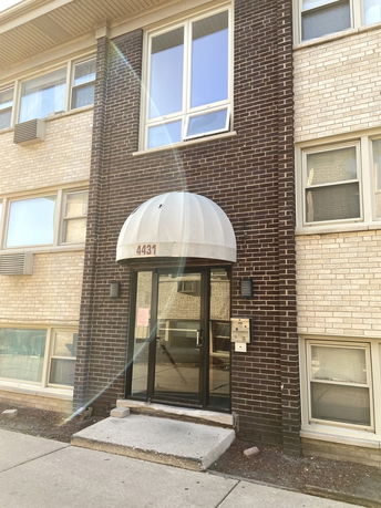 Front view of a multi-story brick building with a glass entrance.