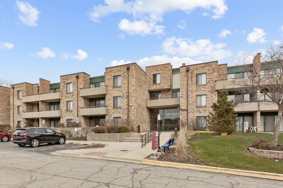 Front view of a multi-story brick apartment building with balconies.