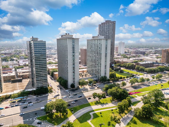Aerial view of tall apartment buildings in an urban area with roads and greenery.