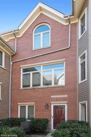 Front view of a brick townhouse with multiple windows and a red door.