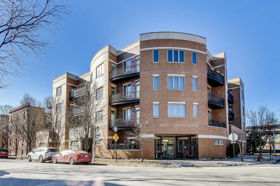 Front view of a multi-story apartment building with curved design and balconies.