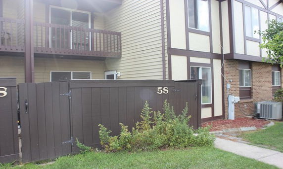 Front view of a multi-story residential building with a balcony and fenced entrance.