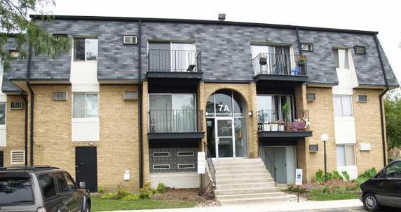 Front view of a multi-story apartment building with balconies and a central entrance.