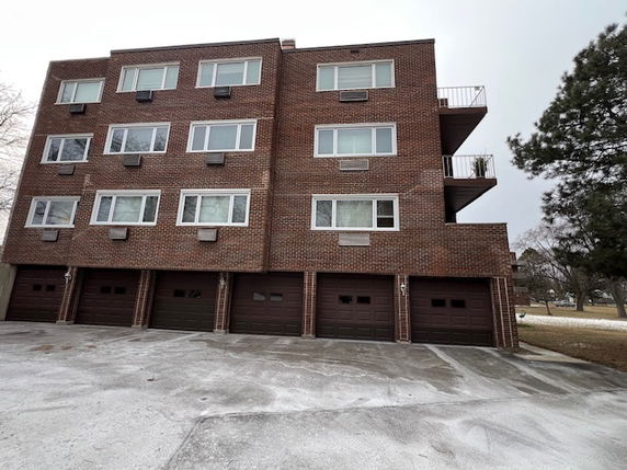 Front view of a multi-story brick building with multiple garages on the ground floor.