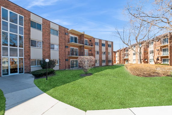 Front view of a three-story brick apartment building with balconies.