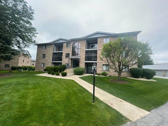 Front view of a three-story apartment building with brick facade and balconies.