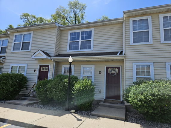 Front view of a two-story townhouse with beige siding and red doors.