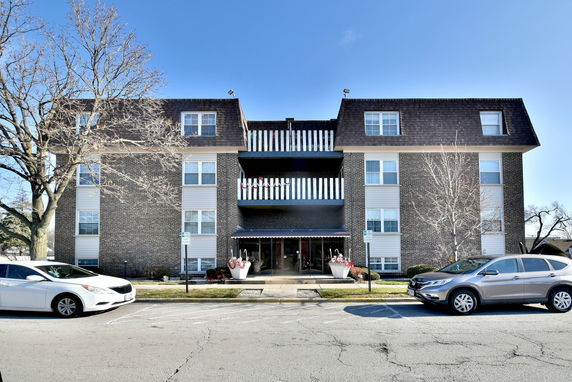 Front view of a three-story brick apartment building with balconies.
