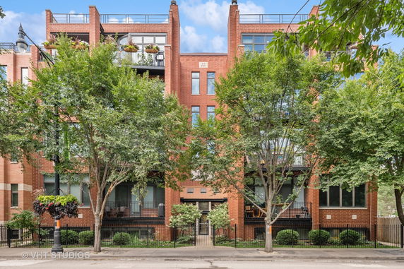 Front view of a multi-story brick residential building with balconies.