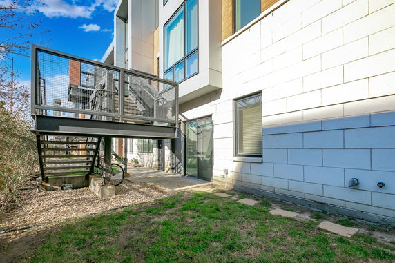 Exterior view of a modern multi-story building with metal stairs and large windows.