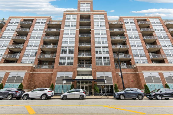 Front view of a multi-story apartment building with balconies and large windows.