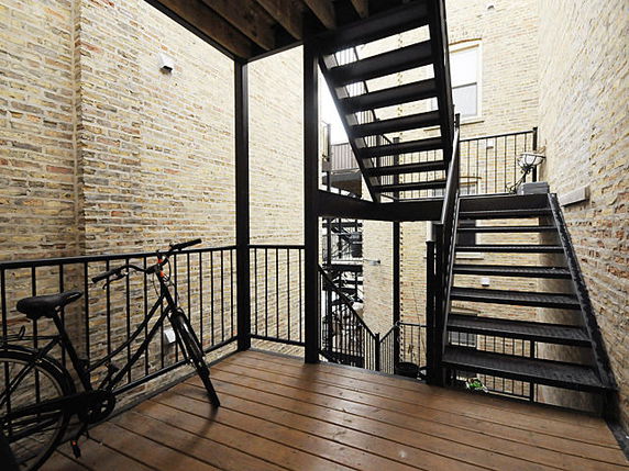 Outdoor staircase area in a building with black metal railings and brick walls.
